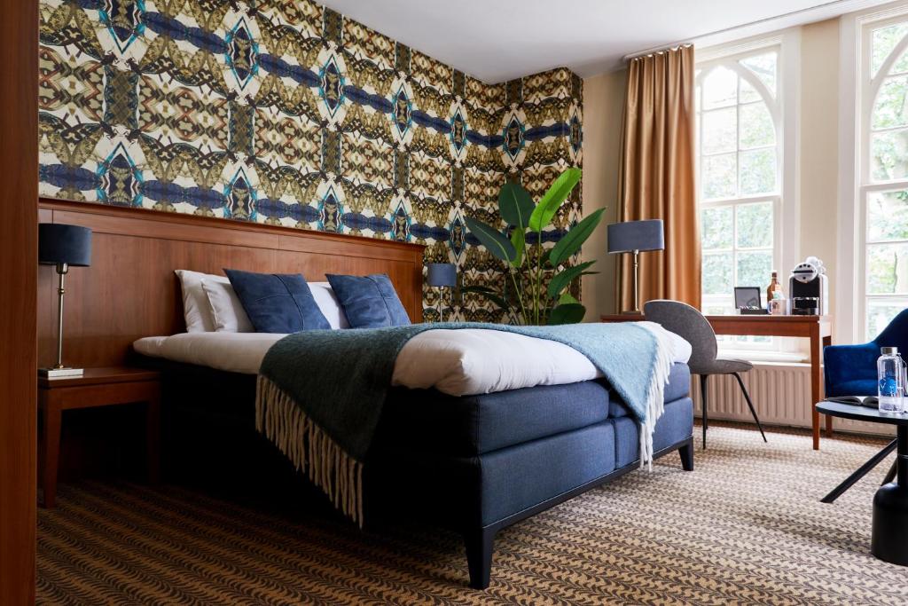 een slaapkamer met een kingsize bed met blauwe kussens bij Kasteel Kerckebosch in Zeist