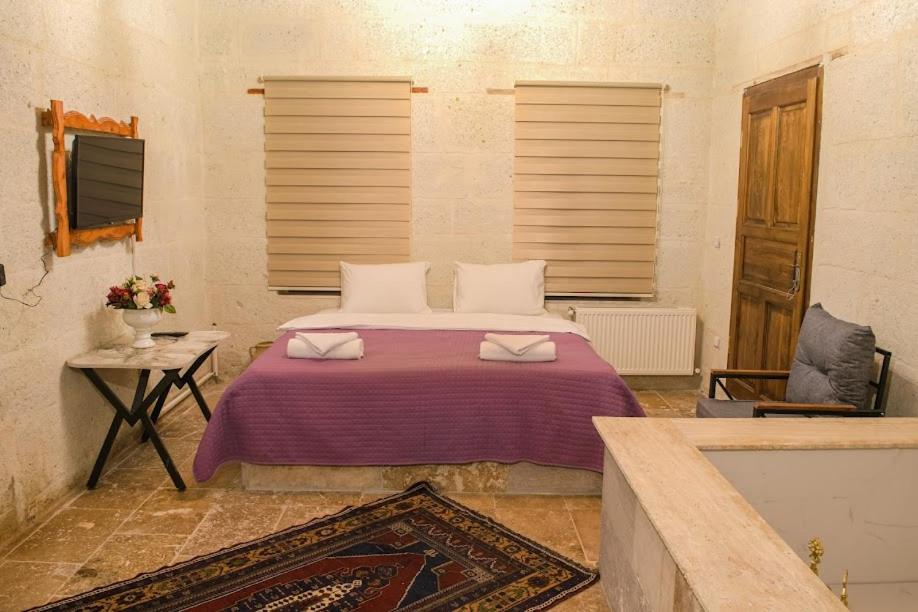 - une chambre avec un lit et une couverture violette dans l'établissement ADA FAMILY SUITE, à Avanos