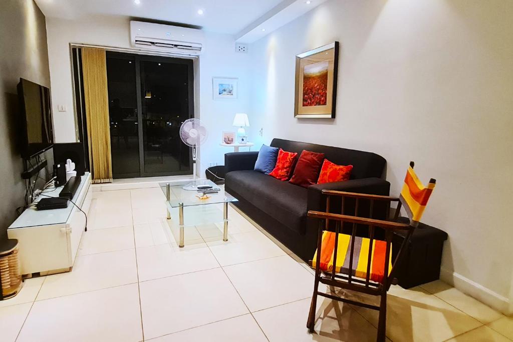 un soggiorno con divano nero e tavolo di Unobstructred seaviews, 2BR, Kingbeds, Fully ACd a Marsaskala