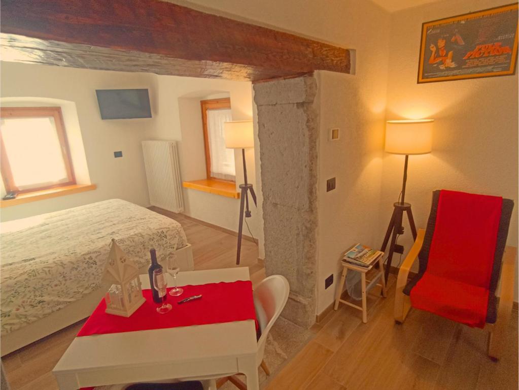 a bedroom with a bed and a table and a red chair at Casa Colibrì - Welcome to a Mountain Dream in Forni di Sopra