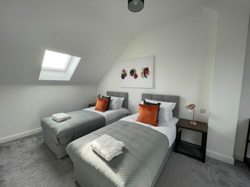 a bedroom with two beds with orange pillows at 3 Bedroom New House with Wi-Fi Sleep 5 By Home Away From Home - A in Newcastle under Lyme