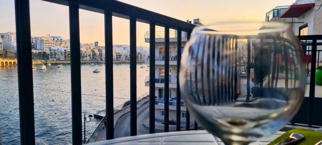 un bicchiere di vino seduto su un balcone con vista sull'acqua di Unobstructred seaviews, 2BR, Kingbeds, Fully ACd a Marsaskala