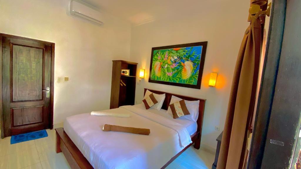 a bedroom with two white beds and a painting on the wall at Padanta Homestay in Gili Trawangan