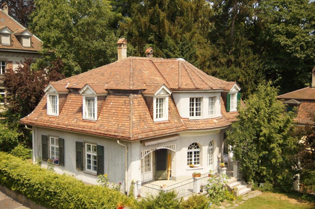 an old white house with a red roof at Bed and Breakfast Wildrose in Bern