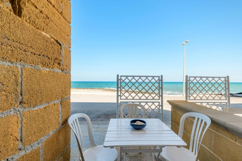une table et des chaises avec la plage en arrière-plan dans l'établissement Casa Helios, à Villanova di Ostuni