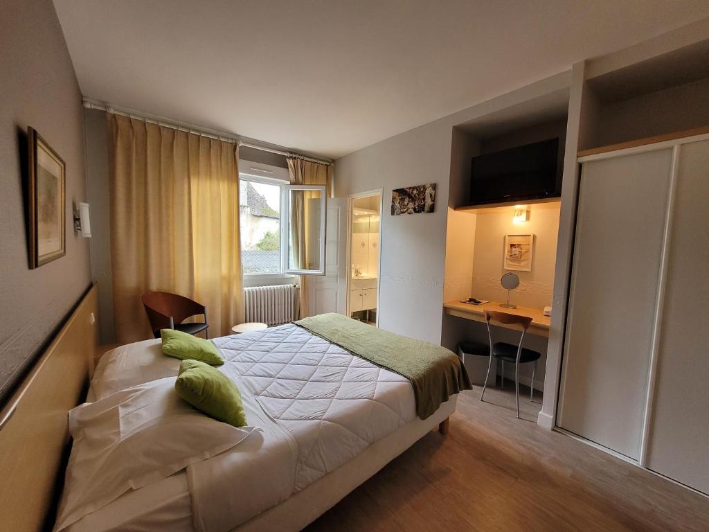 a bedroom with a bed and a desk in it at Hotel Fouillade in Argentat