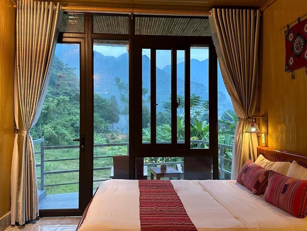 a bedroom with a bed and a large glass window at Nha Tan - Mai Chau Homestay and Tours in Mai Châu