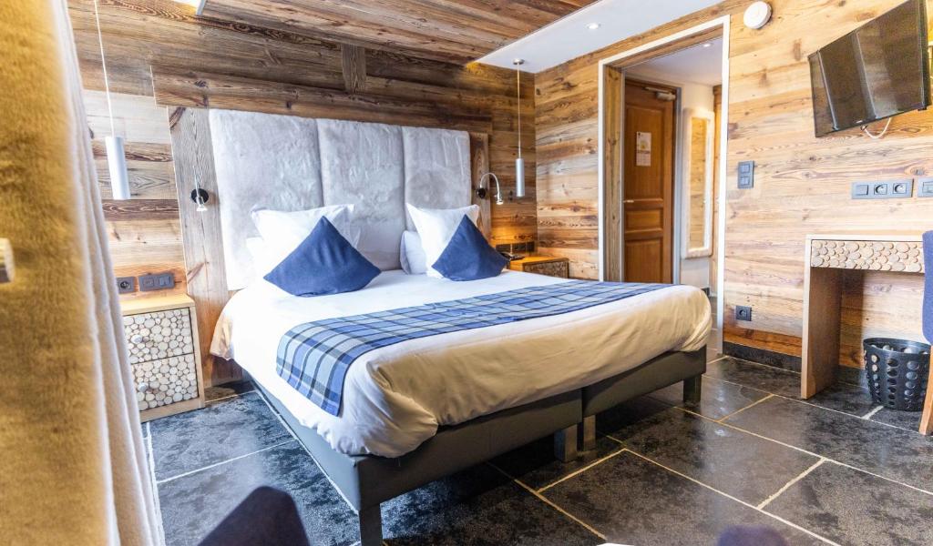 a bedroom with a bed with blue pillows and a fireplace at Hôtel Alpina &amp; SPA in Les Gets
