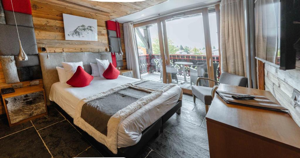 a bedroom with a bed with red pillows on it at Hôtel Alpina &amp; SPA in Les Gets