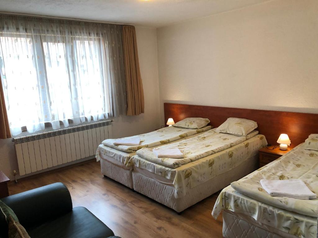 a hotel room with two beds and a chair at Guest Rooms Vachin in Bansko