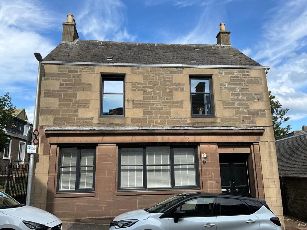 un coche blanco estacionado frente a un edificio de ladrillo en The Old Post Office Double Room (town centre), en Carnoustie