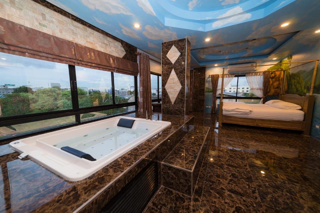 a bathroom with a bath tub and a bedroom at Thongtara House Boutique Srinakarin in Bangkok