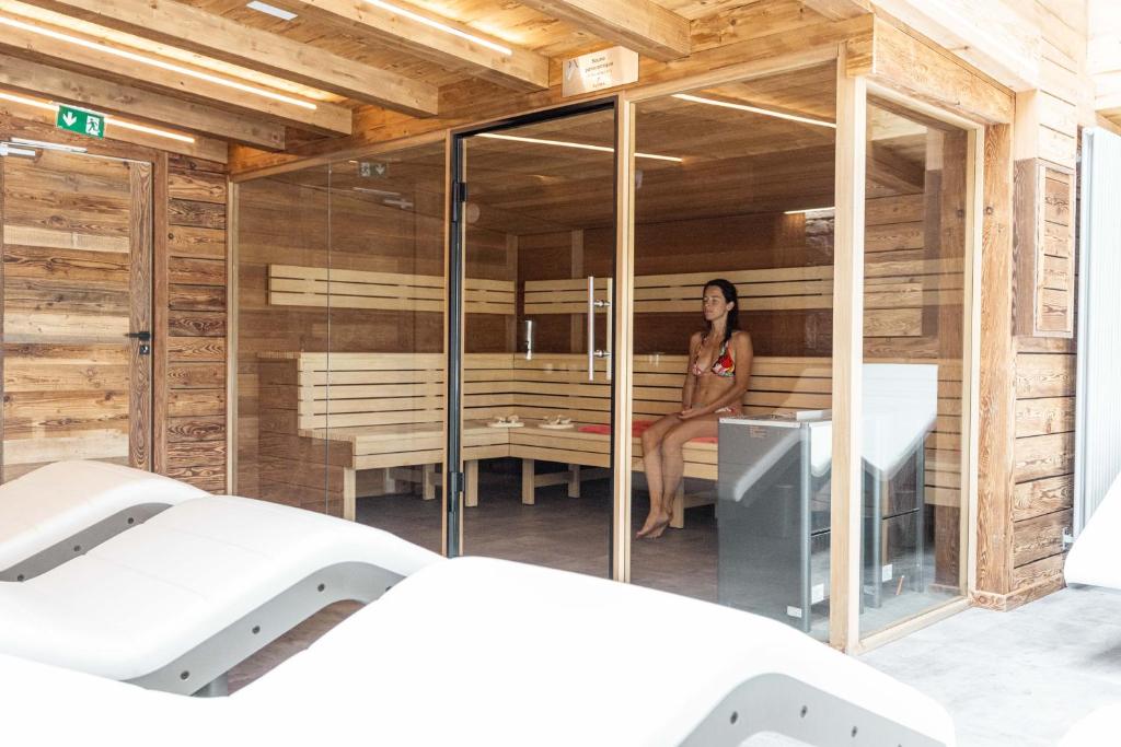 a woman is sitting in a sauna at Hôtel Alpina &amp; SPA in Les Gets