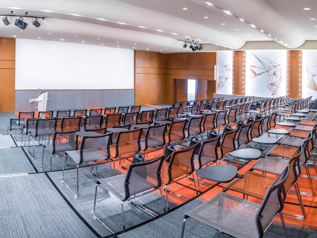 una sala de conferencias con filas de sillas y un podio en Novotel Paris Rueil Malmaison en Rueil-Malmaison