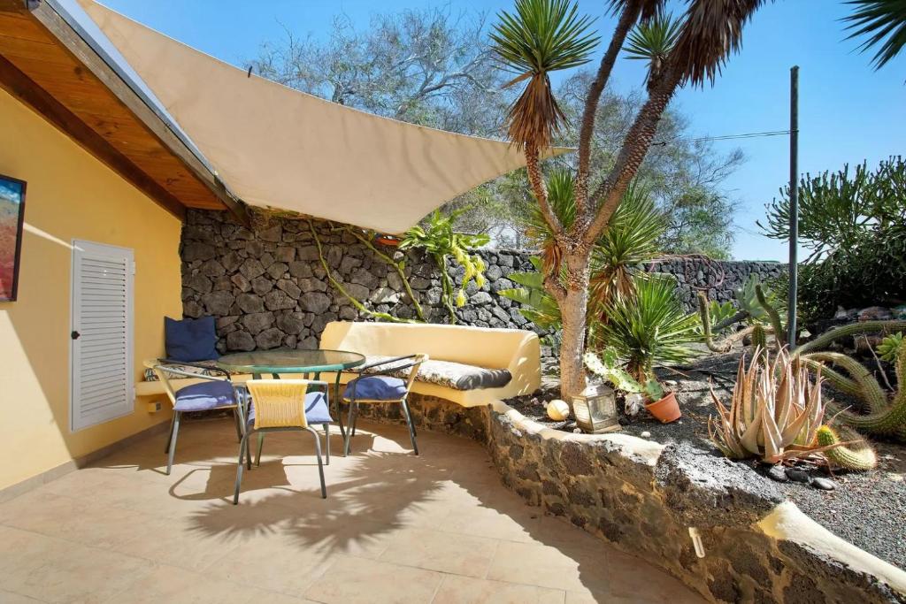a patio with a table and chairs and a stone wall at Casa Verde in Teguise