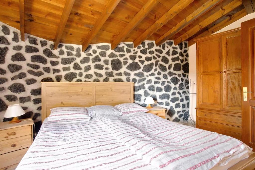a bed in a bedroom with a rock wall at Casa Verde in Teguise