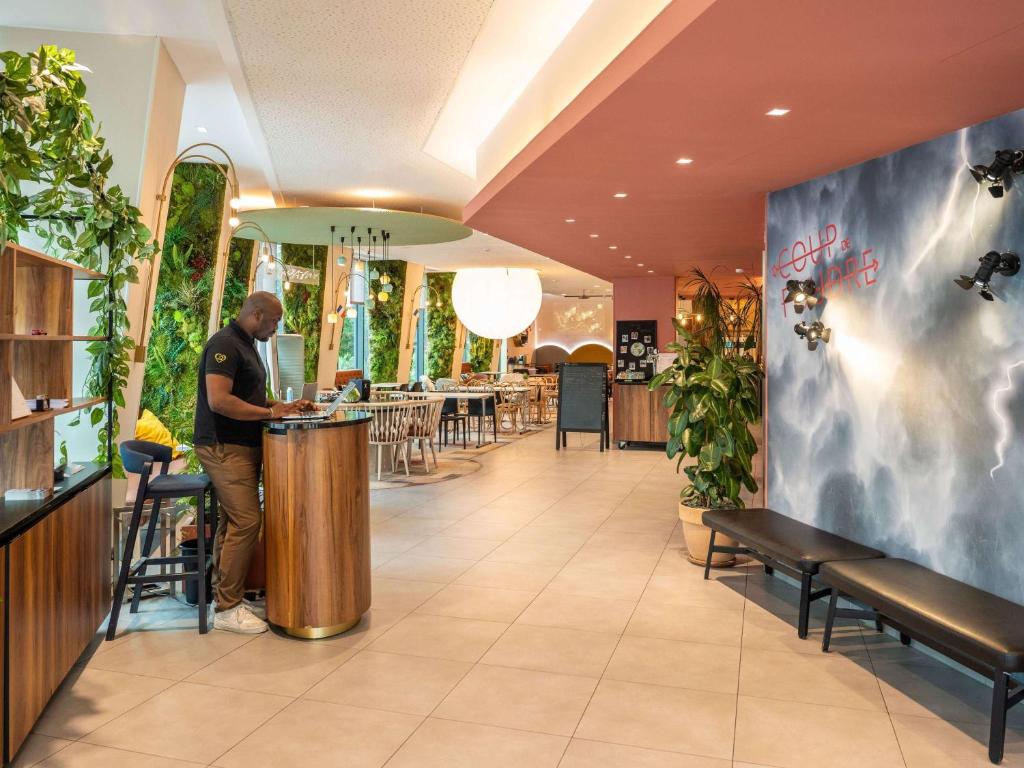 a man standing at a bar in a restaurant at ibis Styles Paris Meteor Avenue d'Italie in Paris