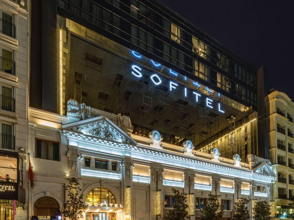 um edifício com um sinal em cima dele à noite em Sofitel Istanbul Taksim em Istambul