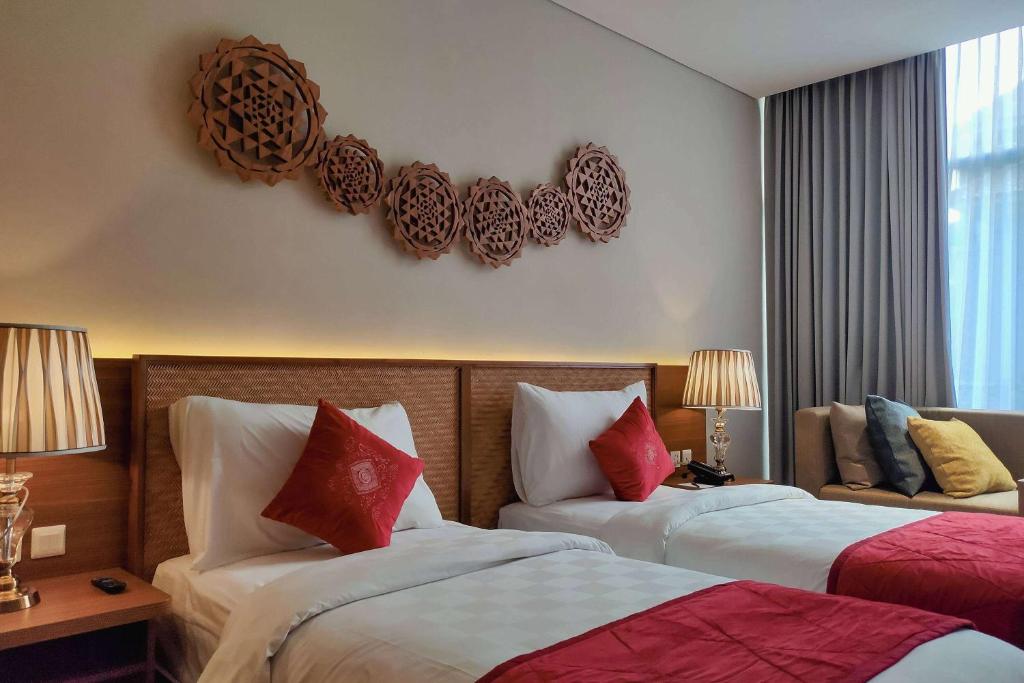 a hotel room with two beds with red and white at Ramada by Wyndham Yogyakarta in Yogyakarta