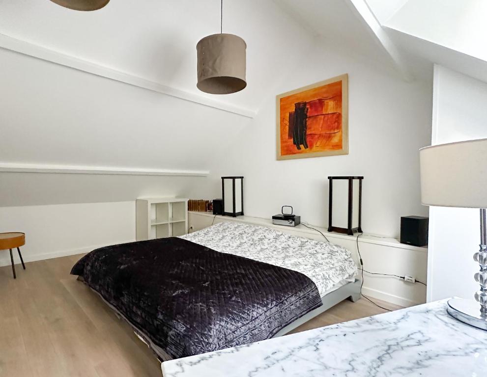 ein Schlafzimmer mit einem schwarzen Bett in einem weißen Zimmer in der Unterkunft Le cottage de David in Pierrefonds