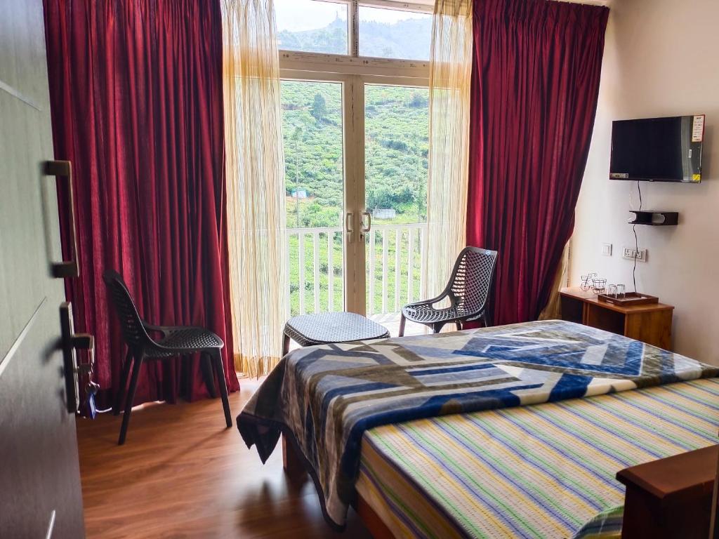 a bedroom with a bed and two chairs and a window at Cloud & Mist Inn, Kotagiri in Kotagiri