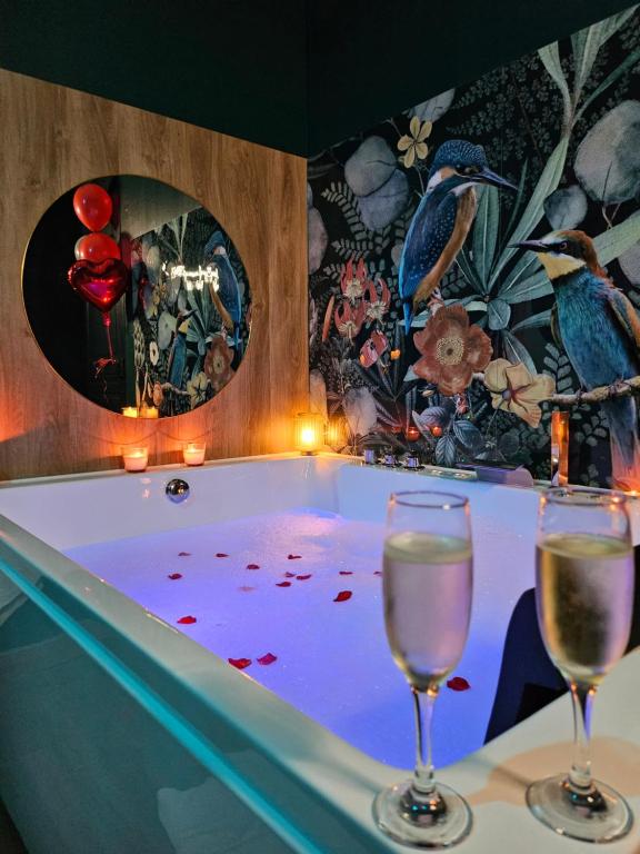 two glasses of wine sitting in a bath tub at Suite Passion - Jacuzzi Spa - Table de massage - 1 Chambre in Saint-Étienne
