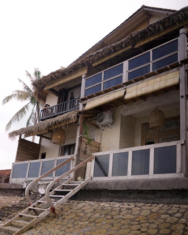 珀尼達島的住宿－La Beach Penida，一座拥有许多窗户和棕榈树的建筑