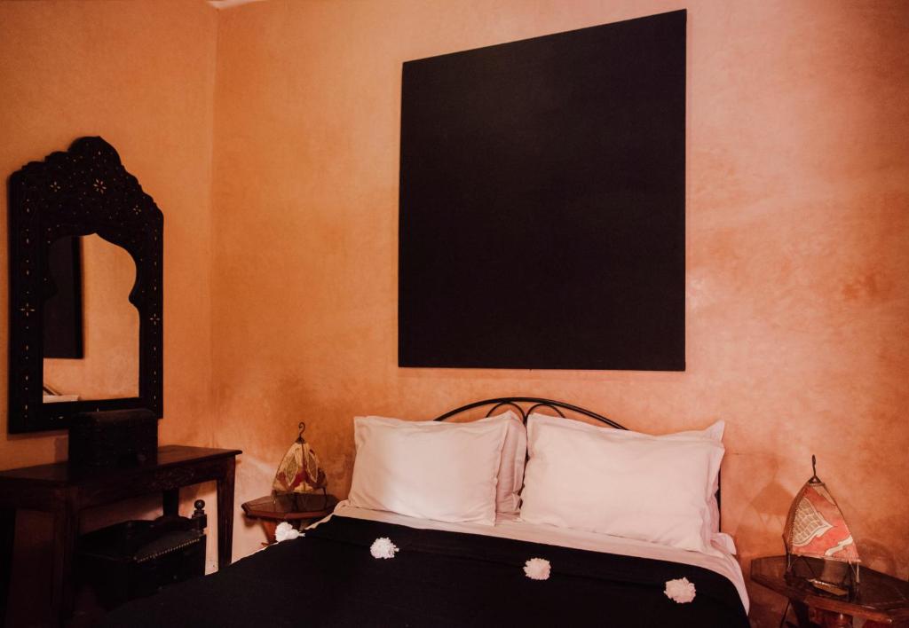 a bedroom with a bed with a black frame and a mirror at Riad Bensaid in Marrakech