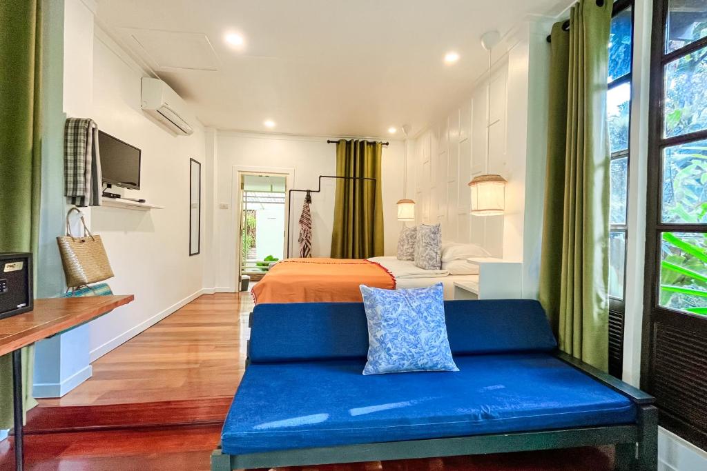 a bedroom with a bed and a blue couch at Baan Bua Cottage SHA EXTRA PLUS B5510 in Ko Kood