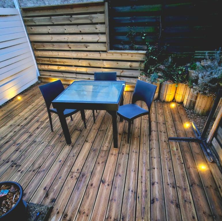 een tafel en stoelen op een houten terras bij Maison de ville avec terrasse et clim in Foucherans