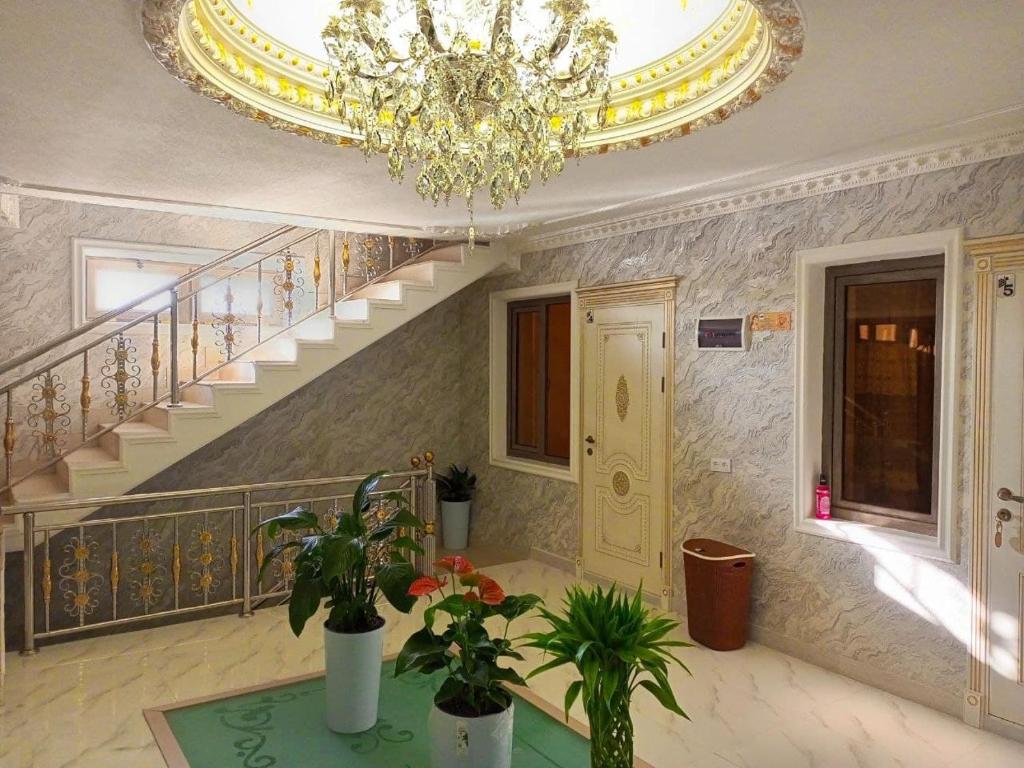 a living room with a chandelier and stairs with plants at Hotel DARI-ZANJIR family guest house in Samarkand