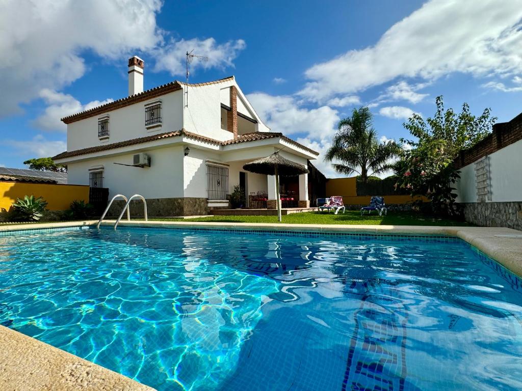 une maison avec une piscine en face d'une maison dans l'établissement Villas Dehesa Roche Viejo, à Conil de la Frontera