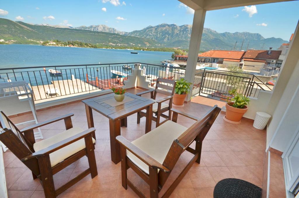 einen Balkon mit Tischen und Stühlen und Blick auf das Wasser in der Unterkunft Apartments Dubravcevic in Tivat