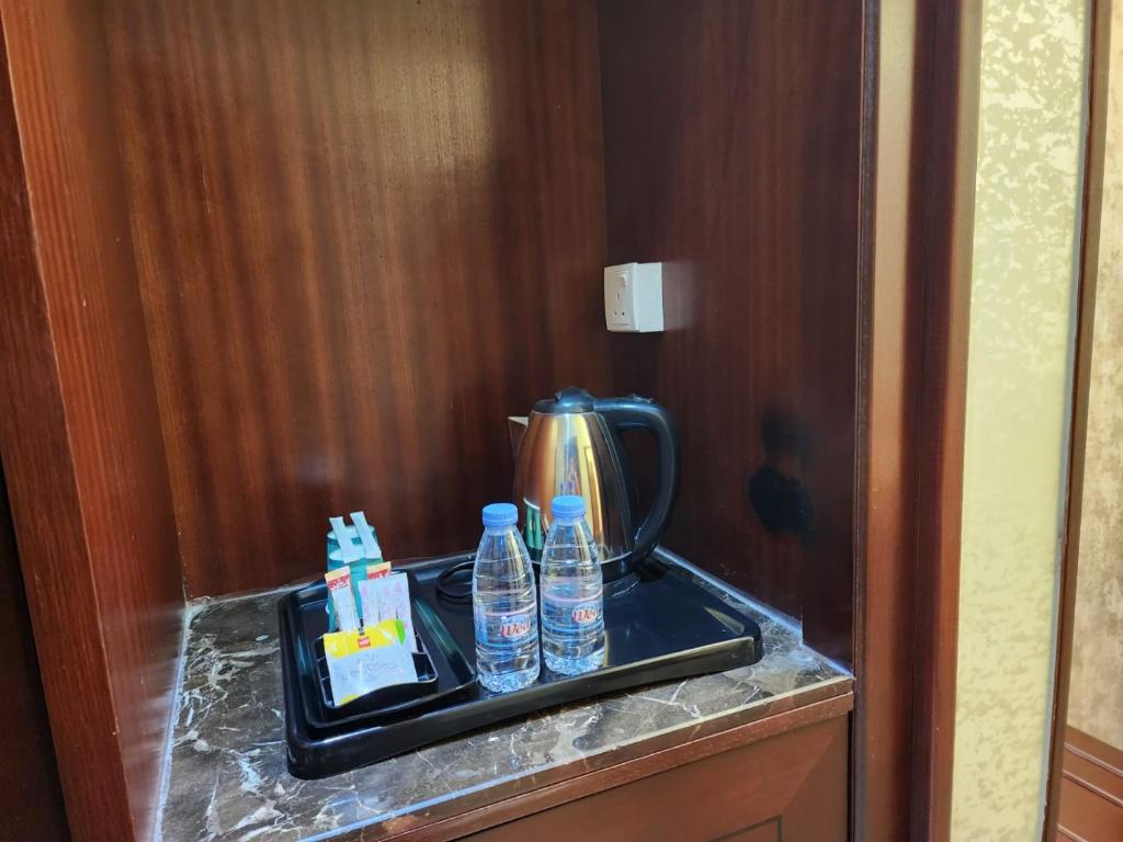 uma bandeja com garrafas de água e uma chaleira para chá em EWG Al Hamra Hotel em Jidá