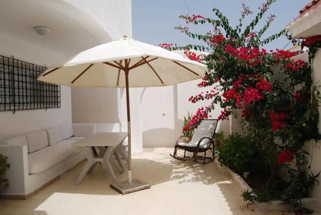 a patio with a bench and an umbrella and flowers at Blue Beach Hostel in Soliman