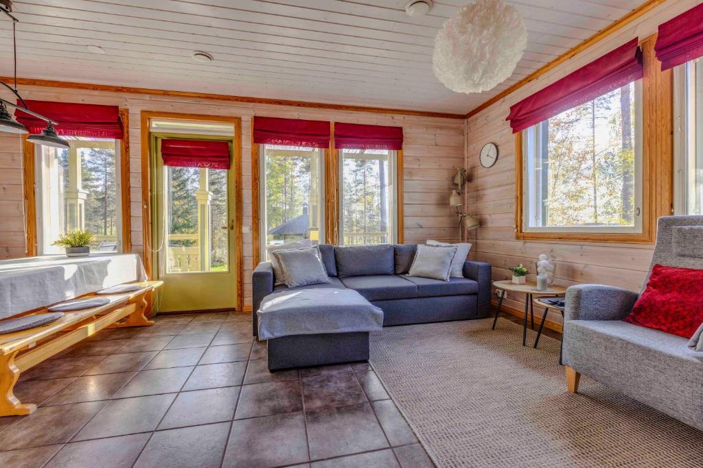 a living room with a couch and chairs and windows at Lomahuvila Himoksen Pistaasi in Jämsä