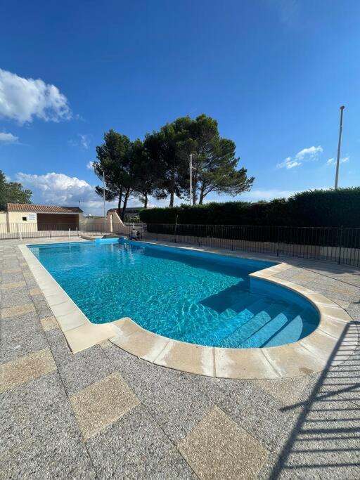 a swimming pool with blue water in a yard at Studio «  Lisbonne » à Avignon in Avignon