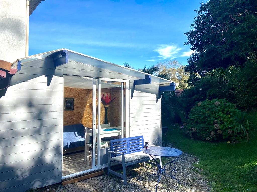 un pequeño cobertizo con un banco azul y una mesa en Studio indépendant au calme à Biarritz en Biarritz