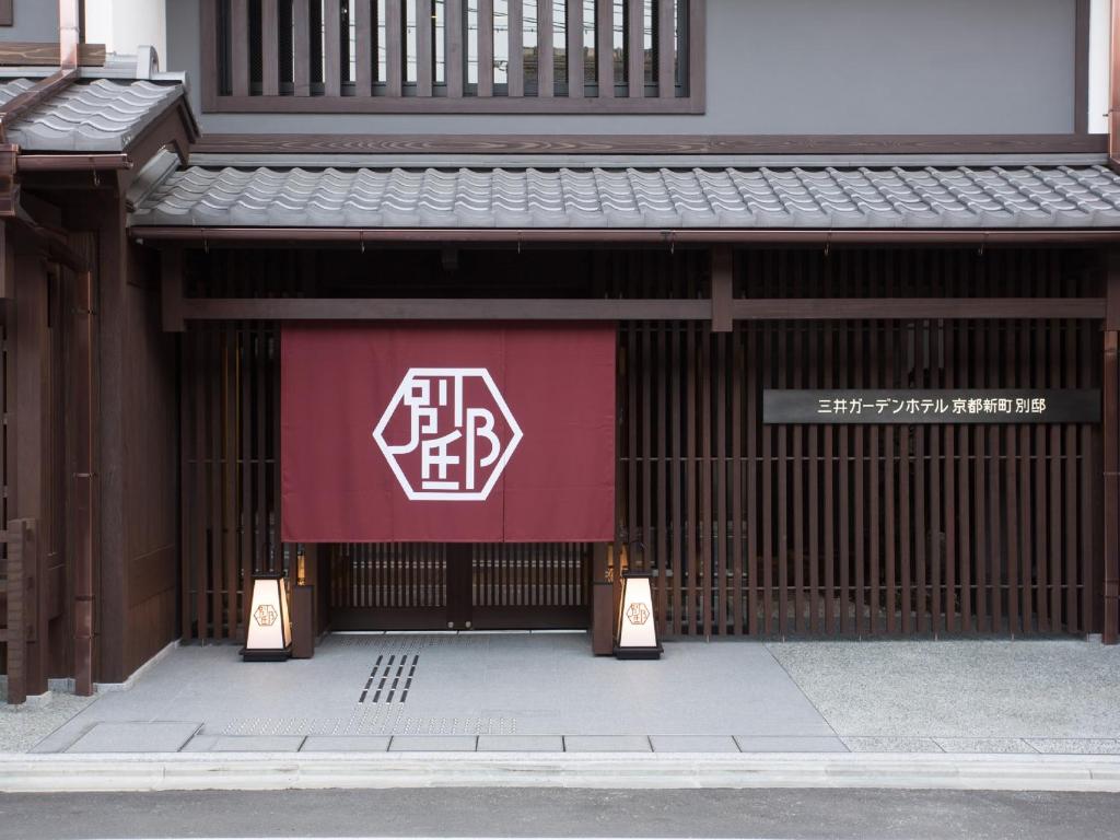 a building with a red and white sign on it at Mitsui Garden Hotel Kyoto Shinmachi Bettei in Kyoto