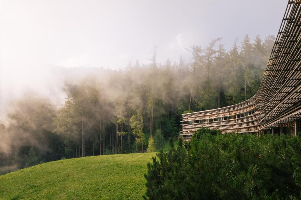 un bâtiment sur le côté d'une colline plantée d'arbres dans l'établissement Vigilius Mountain Resort, à Lana