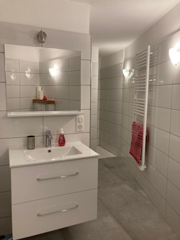 un bagno bianco con lavandino e specchio di Maison SAINTE LUCIE DE PORTO-VECCHIO a Sainte-Lucie de Porto-Vecchio