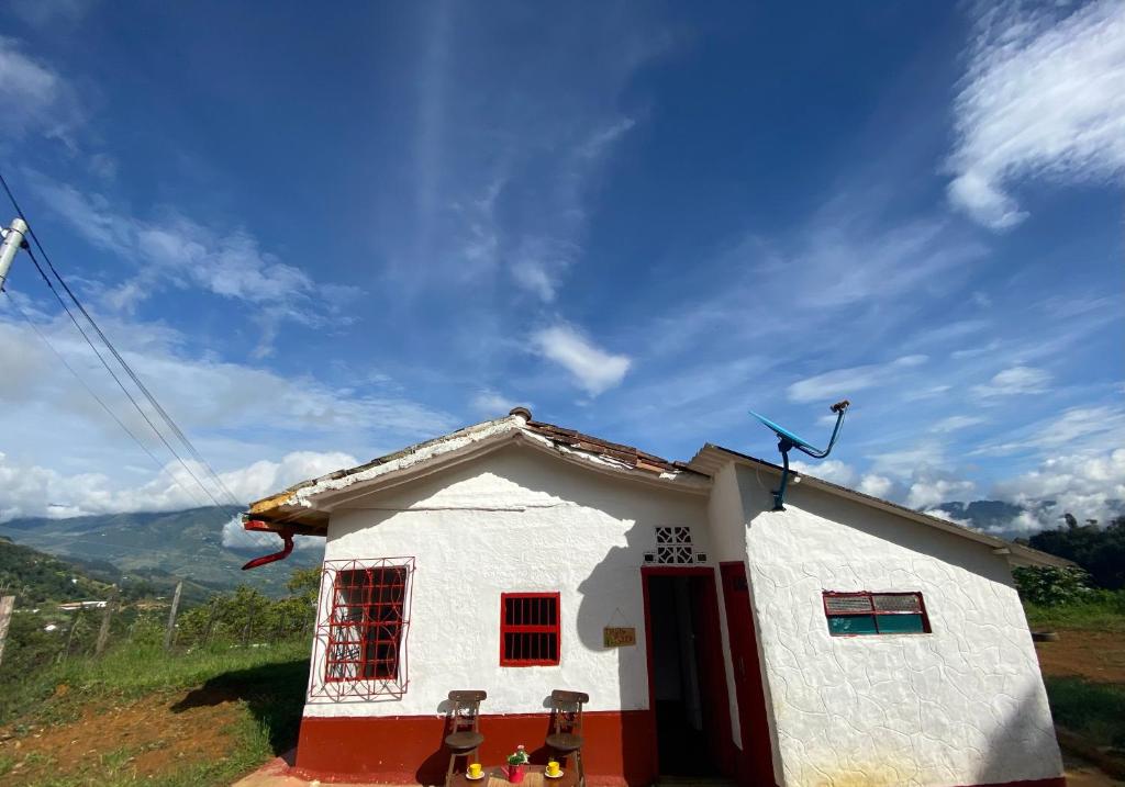 a small white house with red windows on a hill at Cabañita Sauce in Girardota