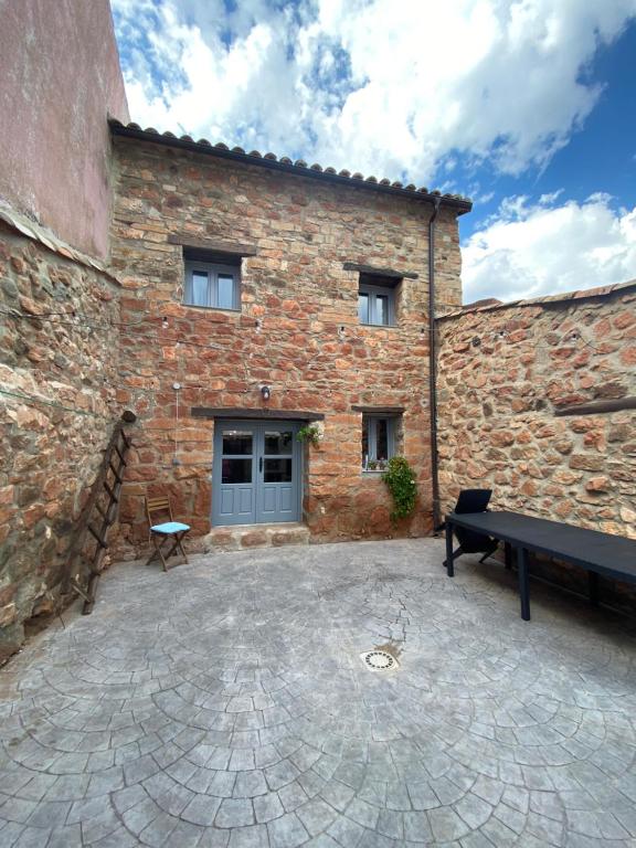 Pálmaces de Jadraque的住宿－La Casa Rural de Pálmaces，前面有长凳的砖砌建筑