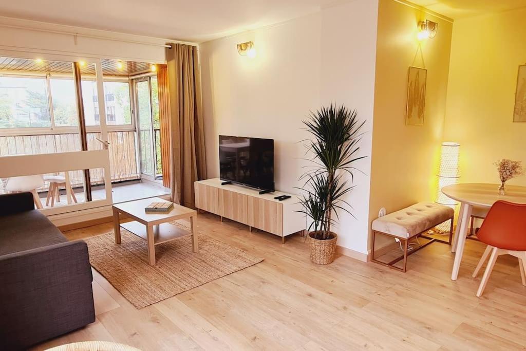 uma sala de estar com um sofá, uma televisão e uma mesa em Appartement neuf proche parc de Versailles + parking em Le Chesnay