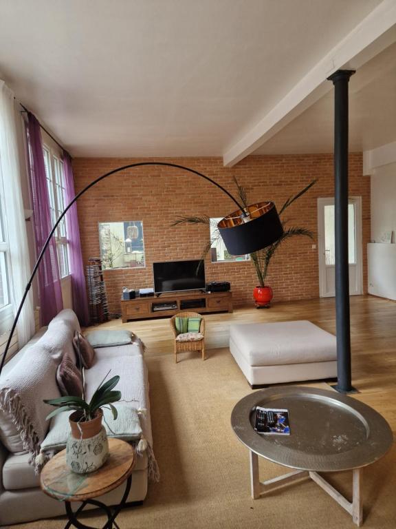 a living room with a brick wall at Loft en duplex 270 m2 & Jardin patio terrasse sauna in Chaville