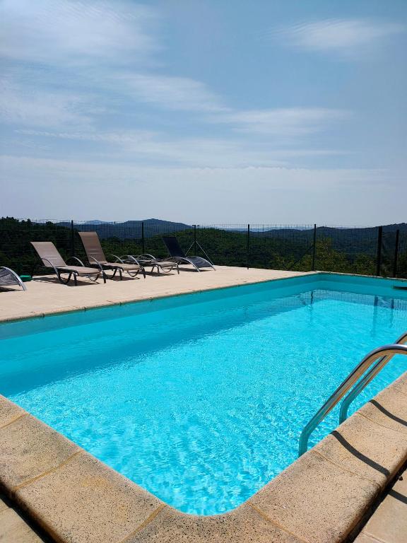 une piscine bleue avec des chaises et une vue dans l'établissement Mazet et maison du Serre dans les Cévennes, à Monoblet