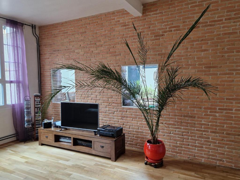 a living room with a tv and a brick wall at Loft en duplex 270 m2 &amp; Jardin patio terrasse sauna in Chaville