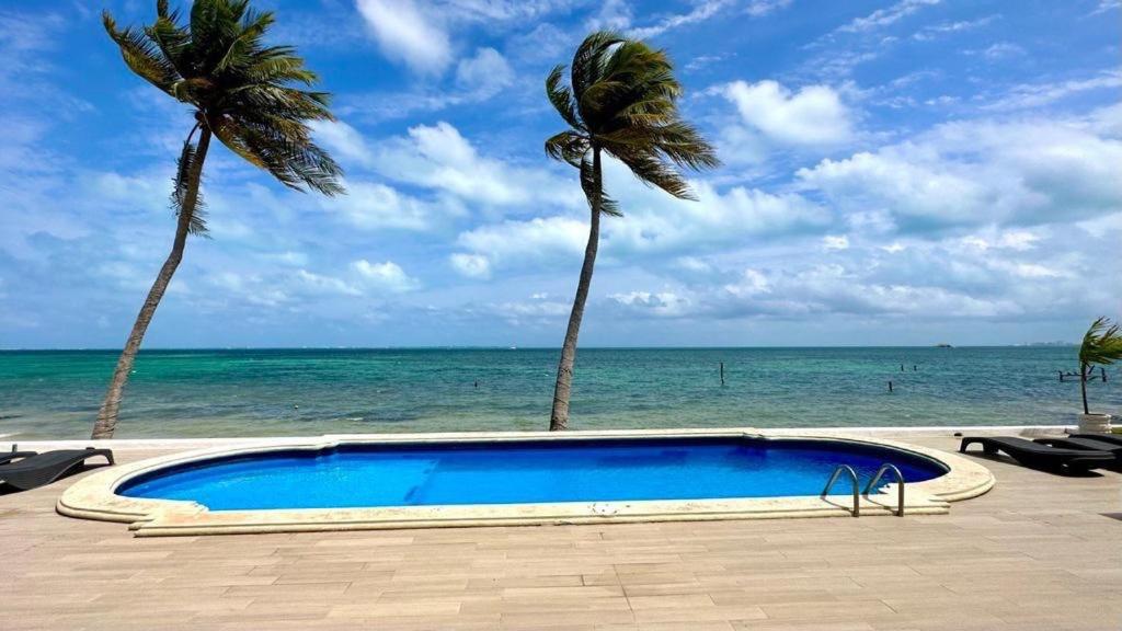 - une piscine bordée de palmiers à côté de l'océan dans l'établissement Flamingo Plus Ocean View, à Cancún