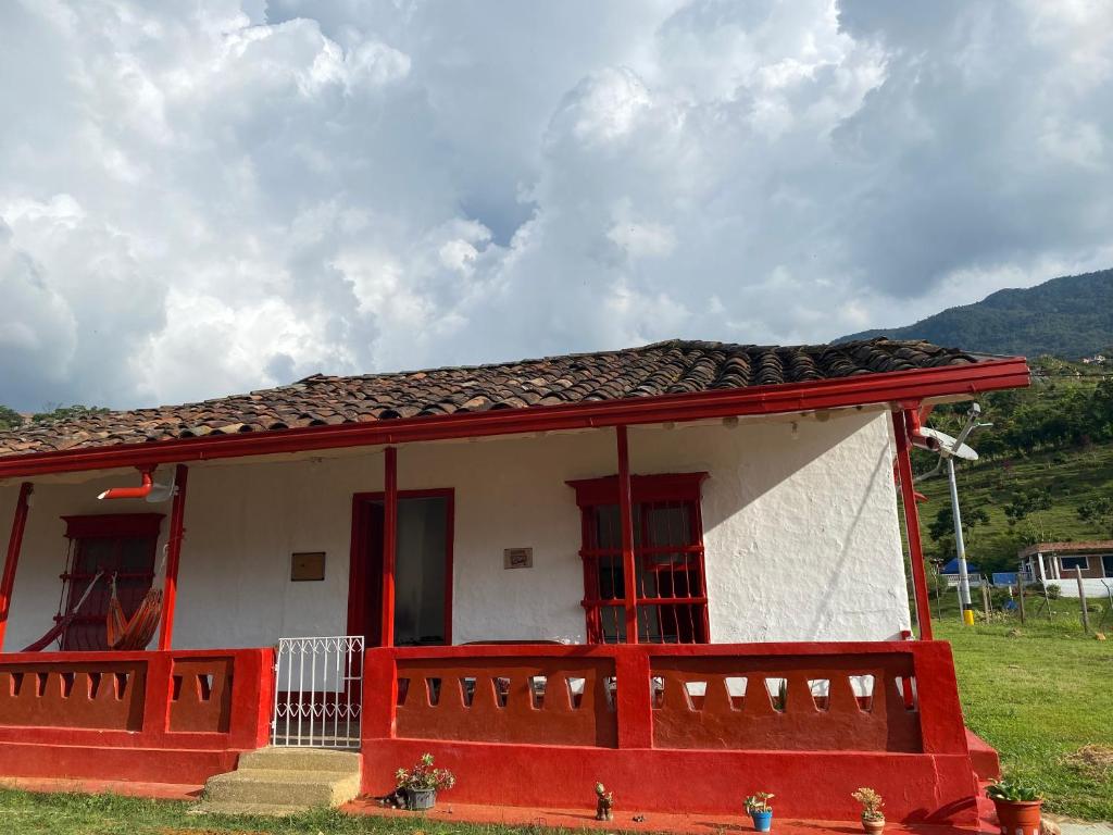 a small red and white house with a porch at Habitación Amapola in Girardota
