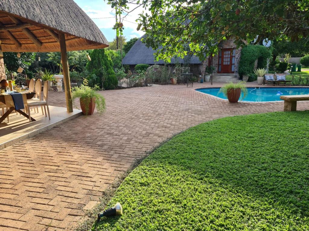 a backyard with a brick patio and a swimming pool at Stone Town Guesthouse in Gaborone